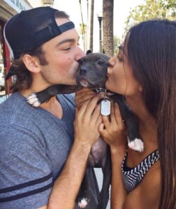Rory Gibson and Alicia Ruelas holding a puppy and kissing it