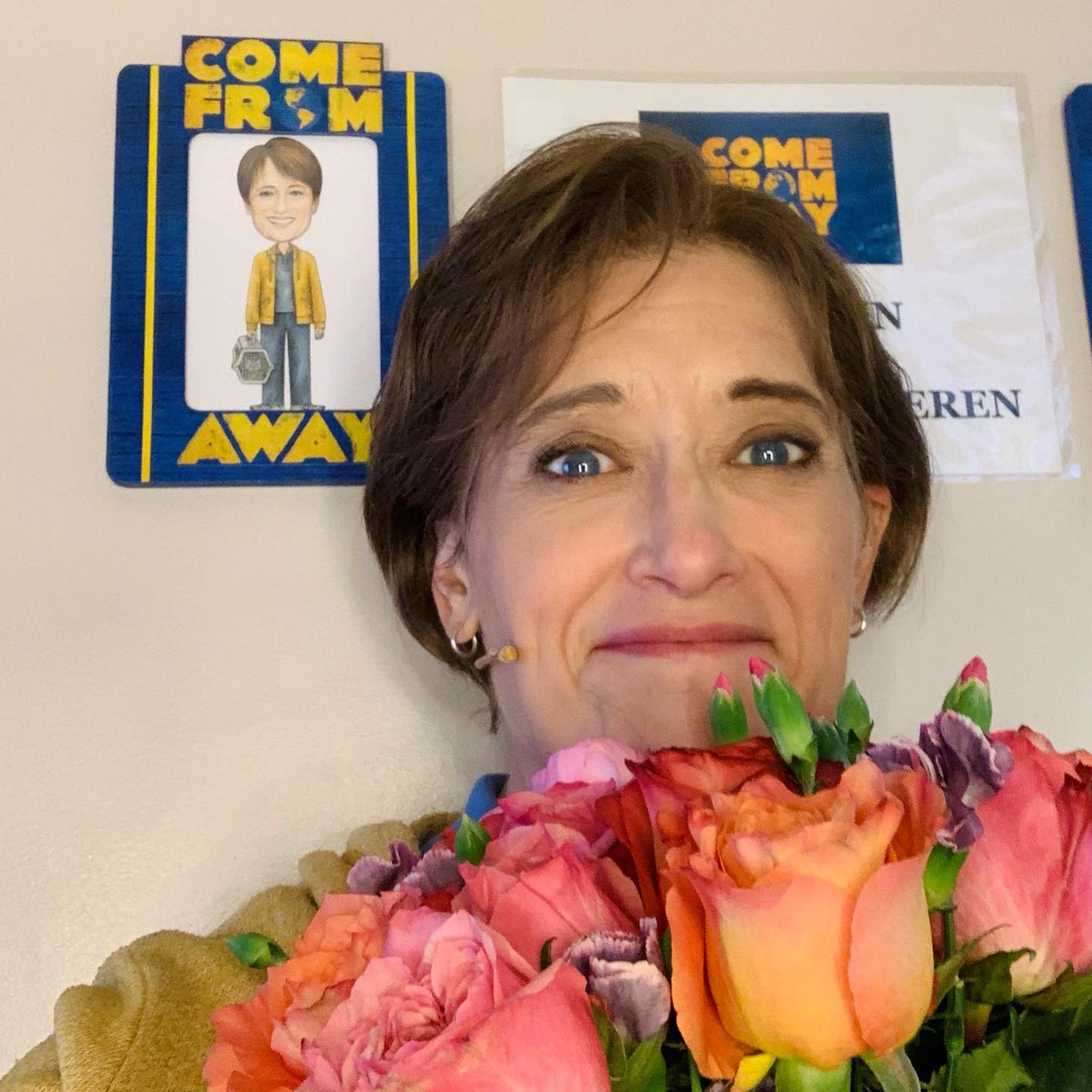 Petrina Bromley holding roses infront of pamphlets of Come From Away