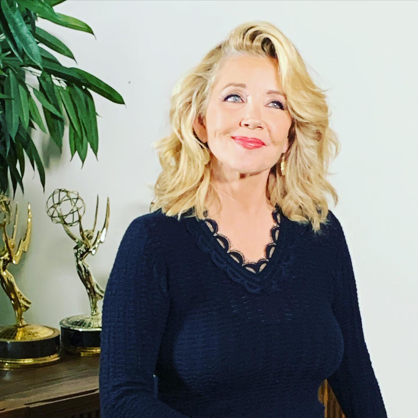 Melody Thomas Scott wearing a black top with her Daytime Emmy Award trophy on the shelf.