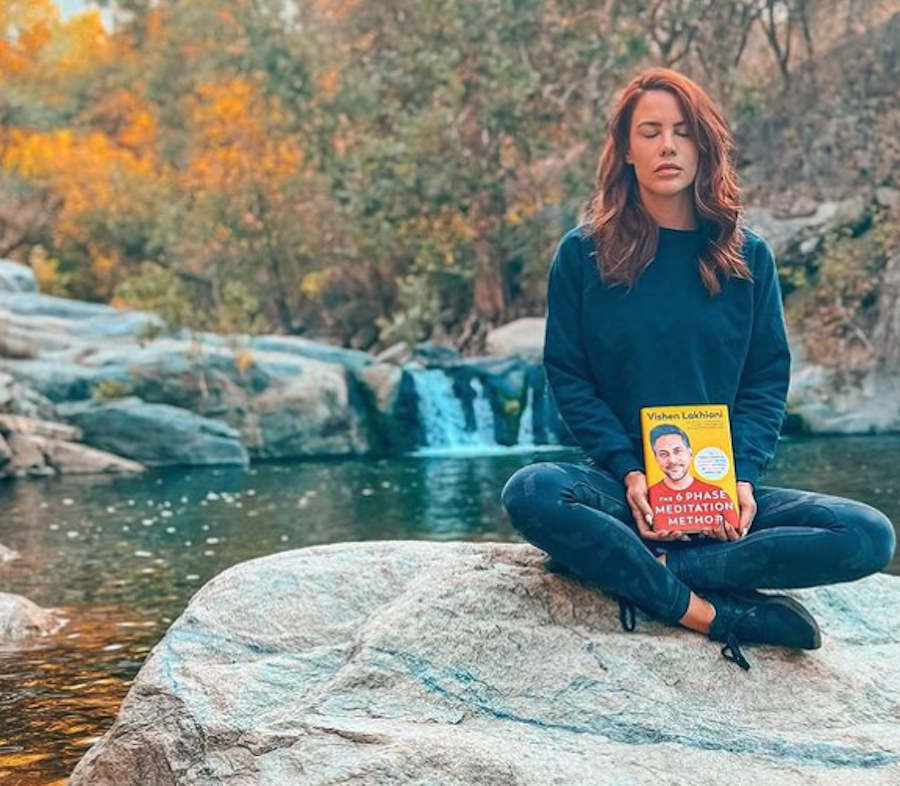 Courtney Hope holding a book about the phases of meditation.