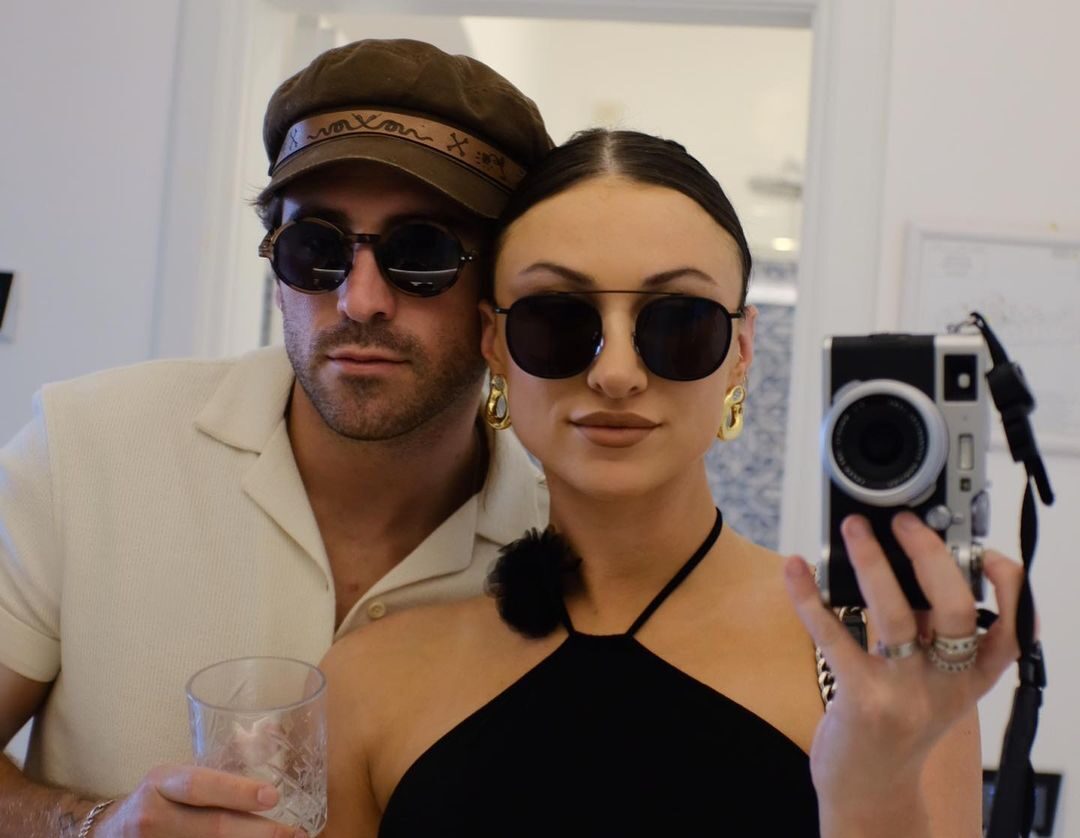 Conner and Carly wearing shades, Carly is holding a camera for a mirror selfie